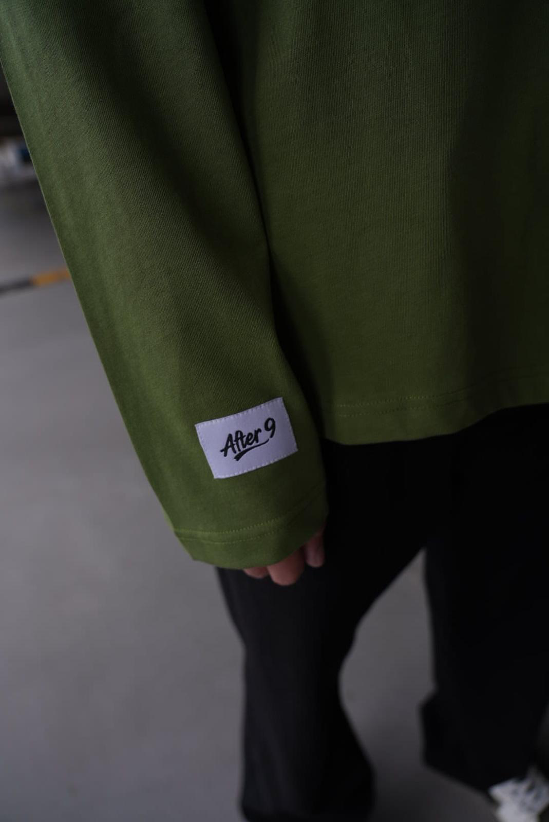 After9 detail — mouwlabel met After 9 logo op de olive longsleeve